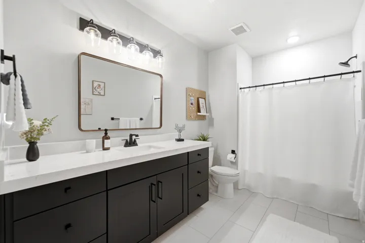 Bathroom featuring a dark wood-finish vanity with a white countertop, rectangular sink, and matte black faucet