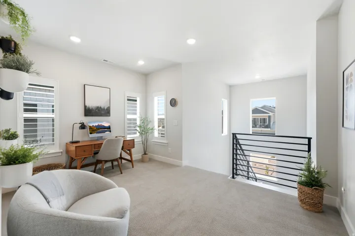Versatile loft space featuring recessed lighting, light gray carpet, and multiple windows with white plantation shutters