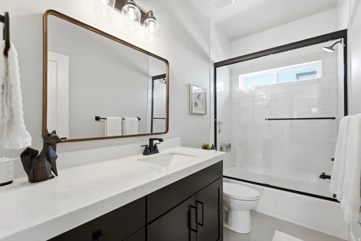 Modern bathroom featuring a single vanity with dark cabinetry, white countertop, and rectangular undermount sink