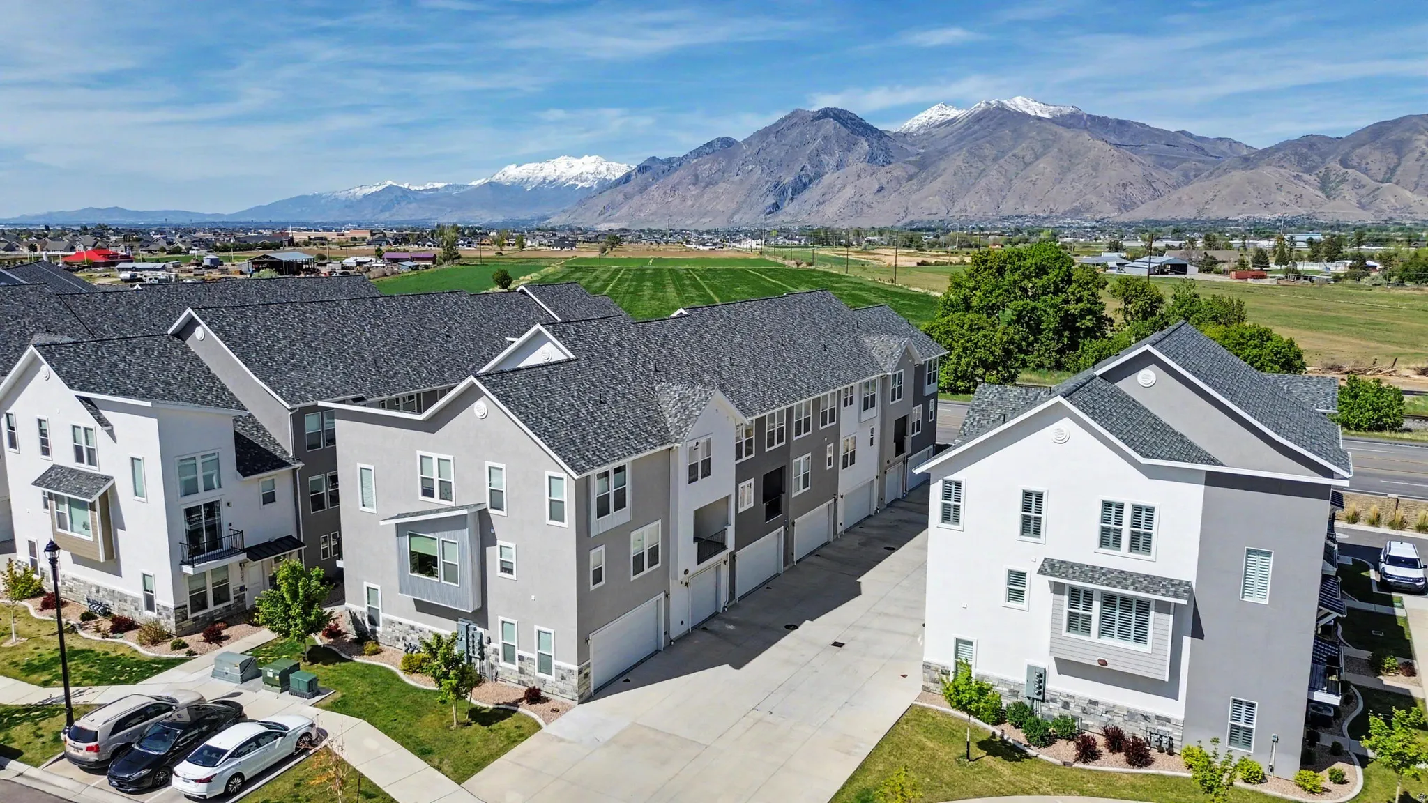 Modern multi-story residential buildings featuring varied siding, attached garages, and a mountain backdrop