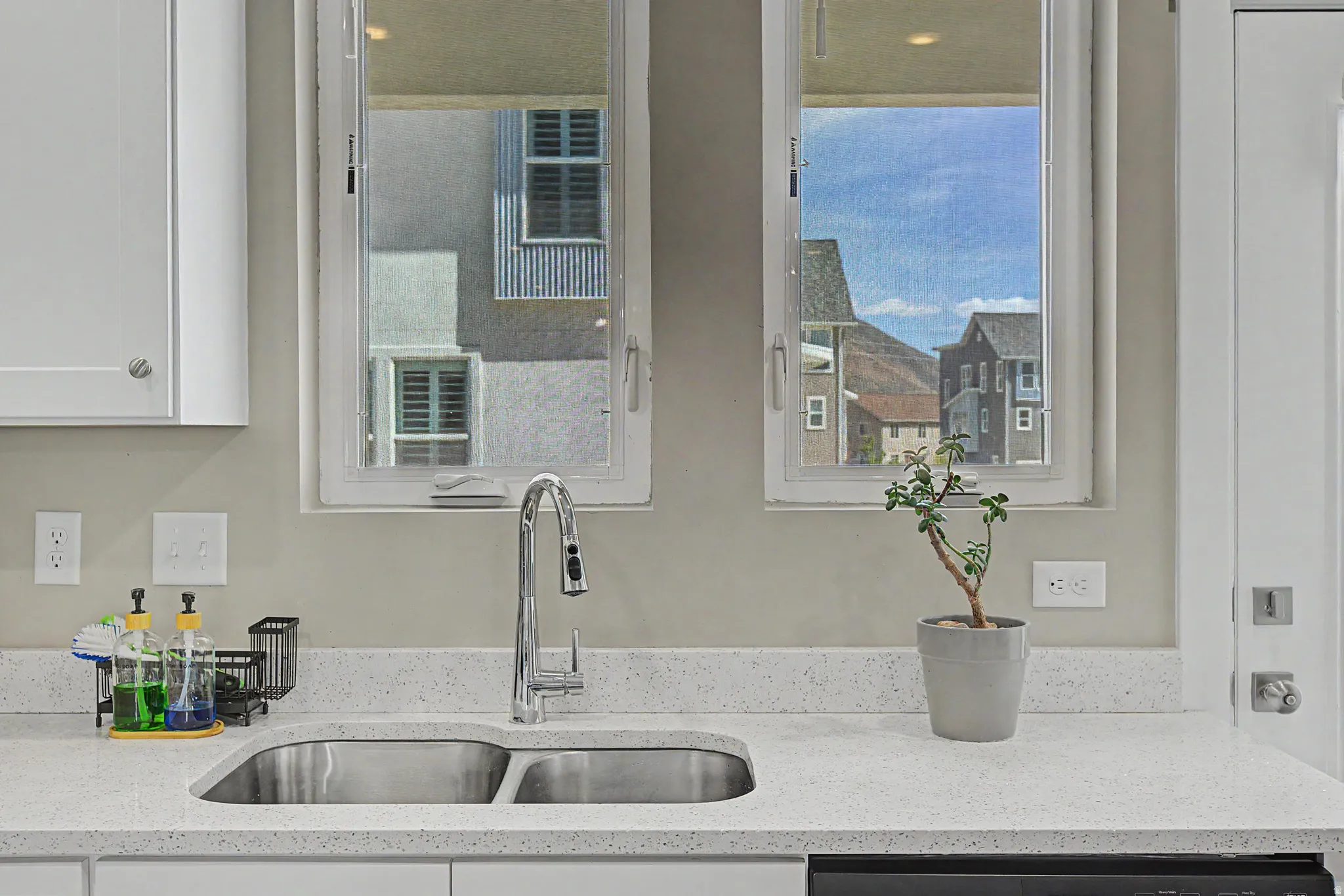 Dual basin stainless steel sink with a high-arch chrome faucet set against a speckled white countertop