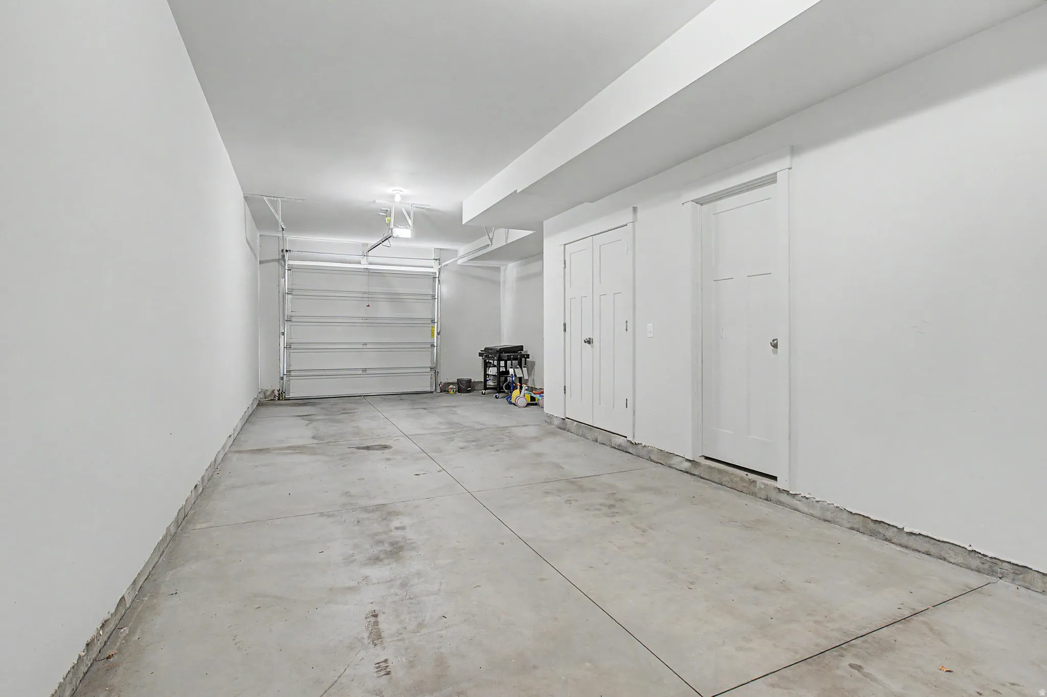 Spacious garage featuring a concrete floor, bright white walls, and an overhead garage door