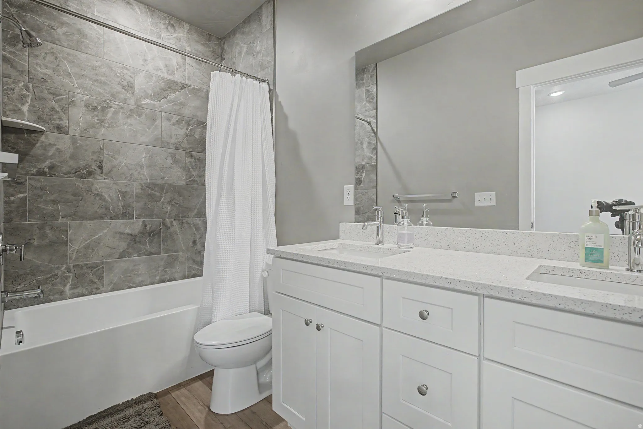 Bathroom featuring a large vanity with dual undermount sinks, light-toned countertop, and white cabinetry