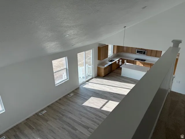 Open-concept living area with wood-finish flooring, a sliding glass door, and multiple windows