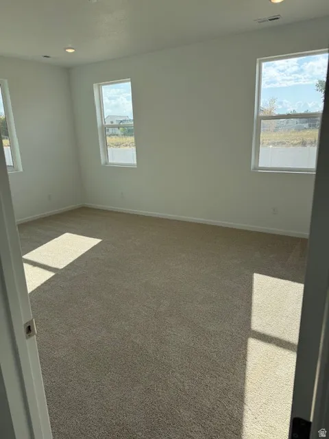Neutral toned carpeting with recessed lighting and multiple windows