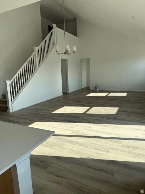 Vaulted ceilings, wood-finish flooring, and a chandelier illuminate a bright open-concept space