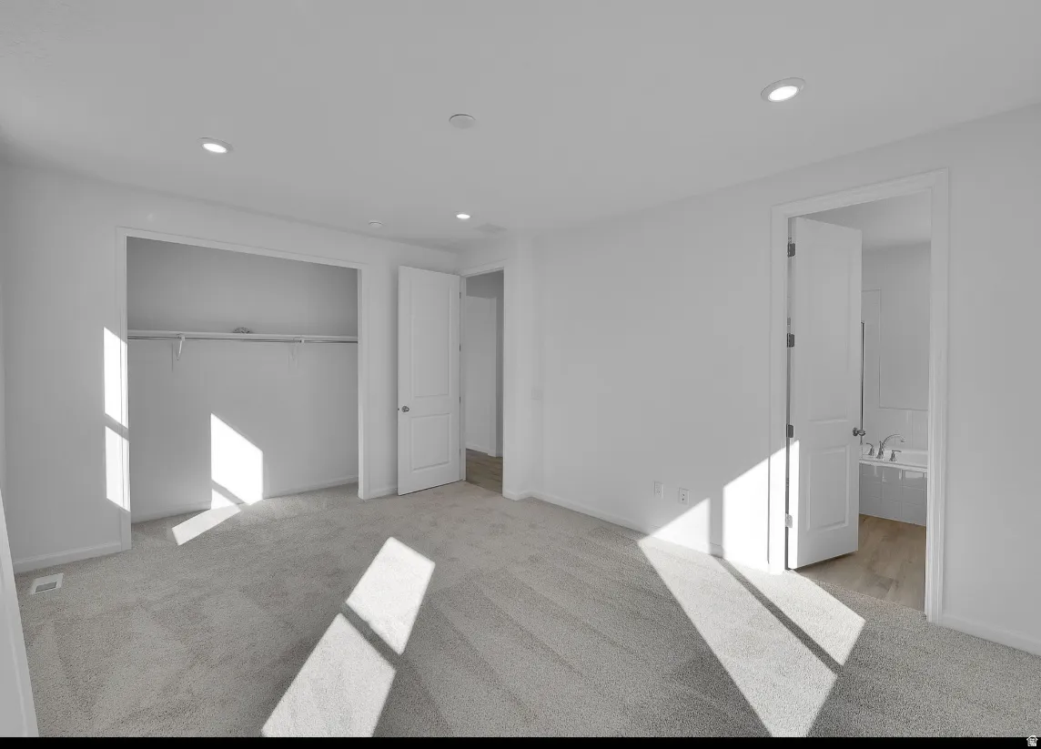 Photo of another Model Home. This home will feature Darker Cabinets and finishes. For Size and inspiration purposes only. Spacious room featuring light gray carpeting, recessed ceiling lighting, a built-in closet with shelving and hanging rod, and a white