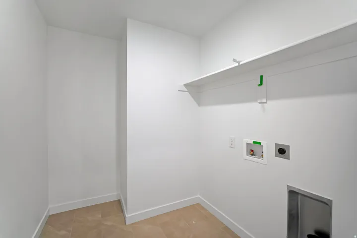 Utility room featuring tile flooring, white walls, built-in shelving, and appliance hookups. Photo of another Model Home. This home will feature Darker Cabinets and finishes. For Size and inspiration purposes only.