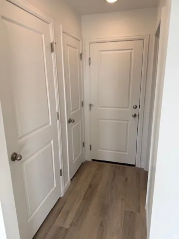 Wood-finish flooring with white paneled doors and recessed ceiling lighting