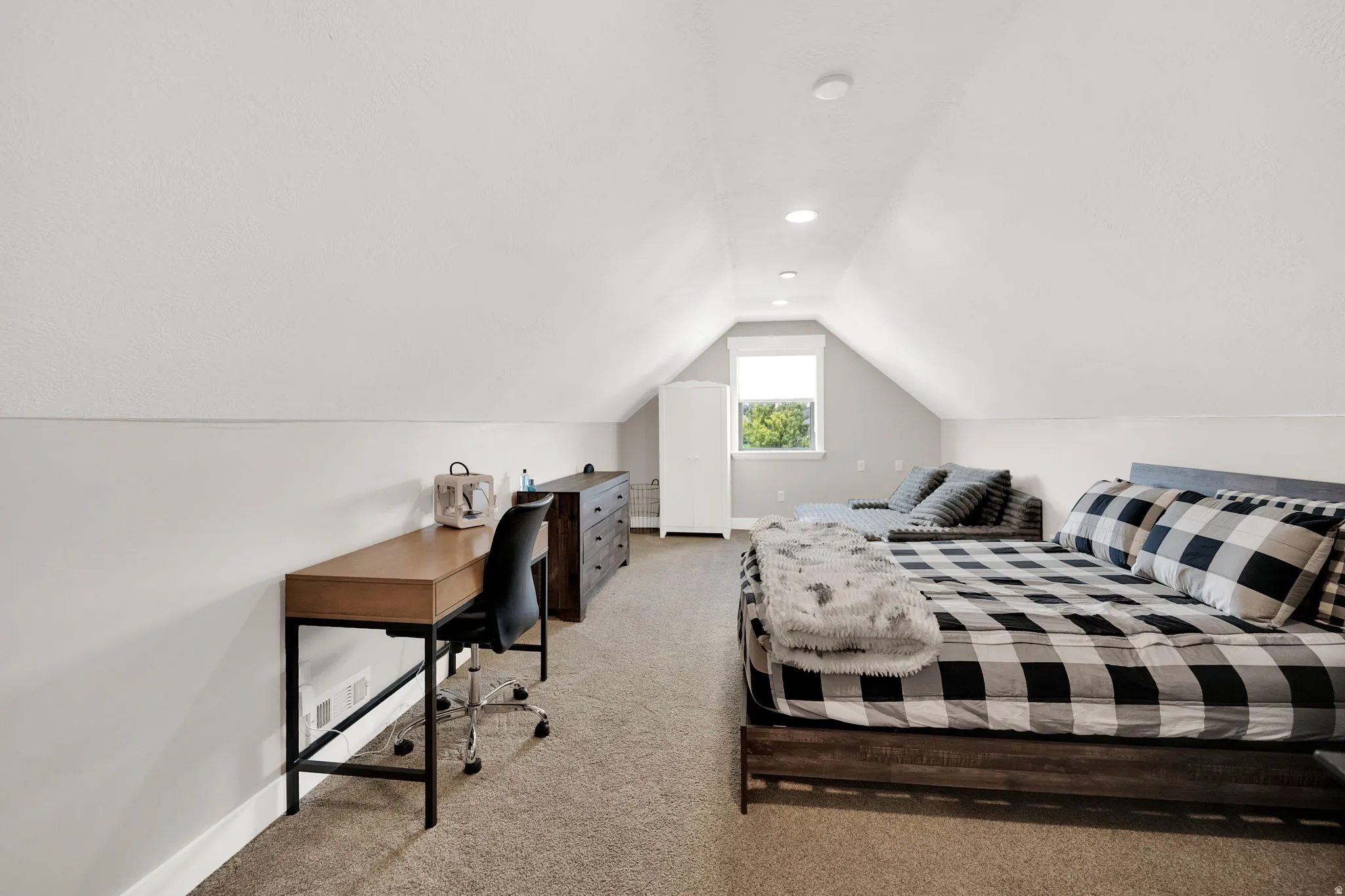 Spacious room featuring vaulted ceilings, recessed lighting, neutral-toned carpeting, and a built-in window