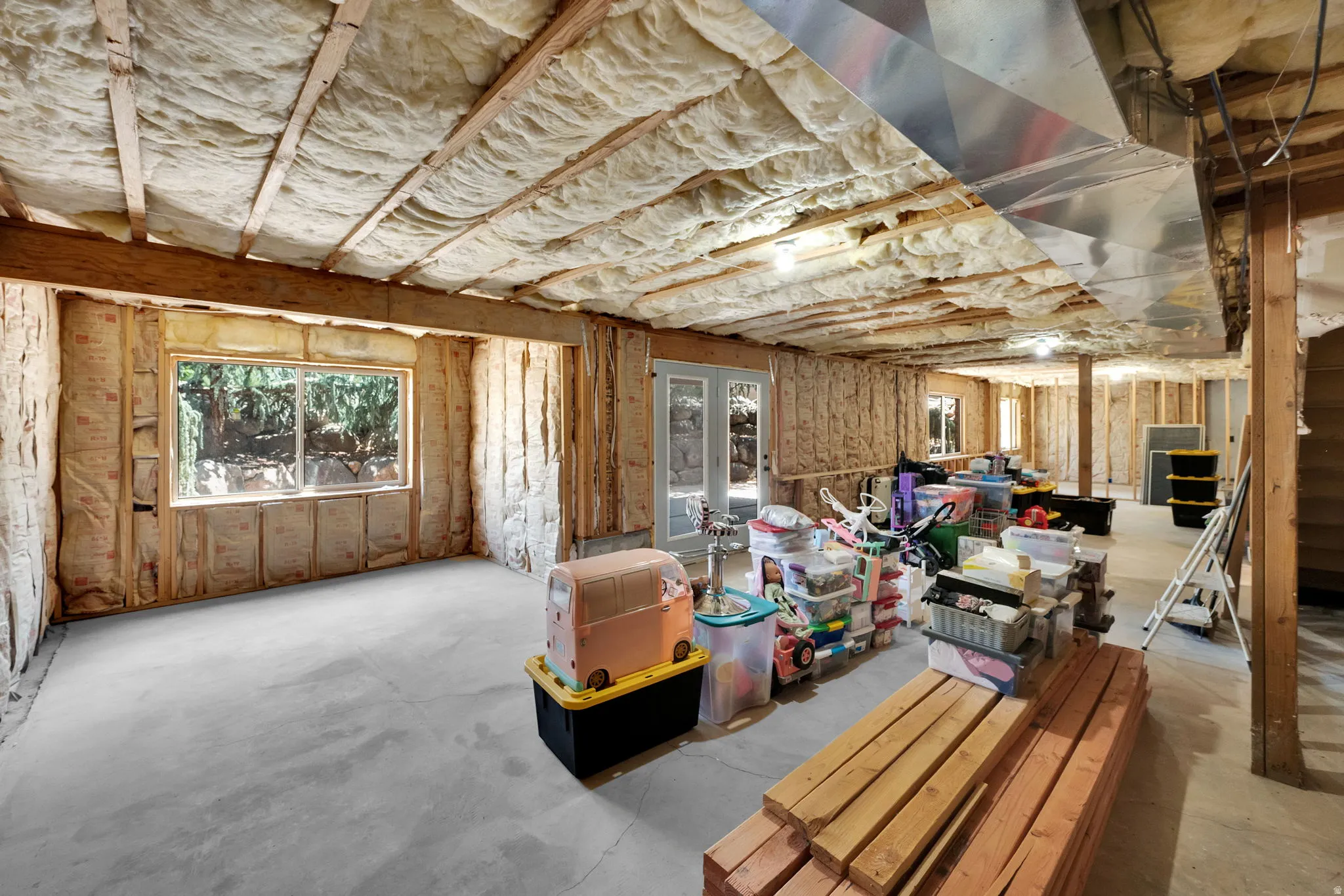 Unfinished lower level with exposed ceiling joists and insulation