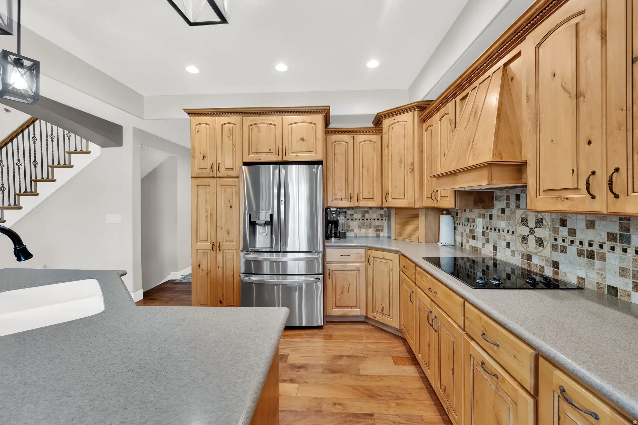 Kitchen featuring wood cabinetry, stainless steel refrigerator, and a built-in cooktop