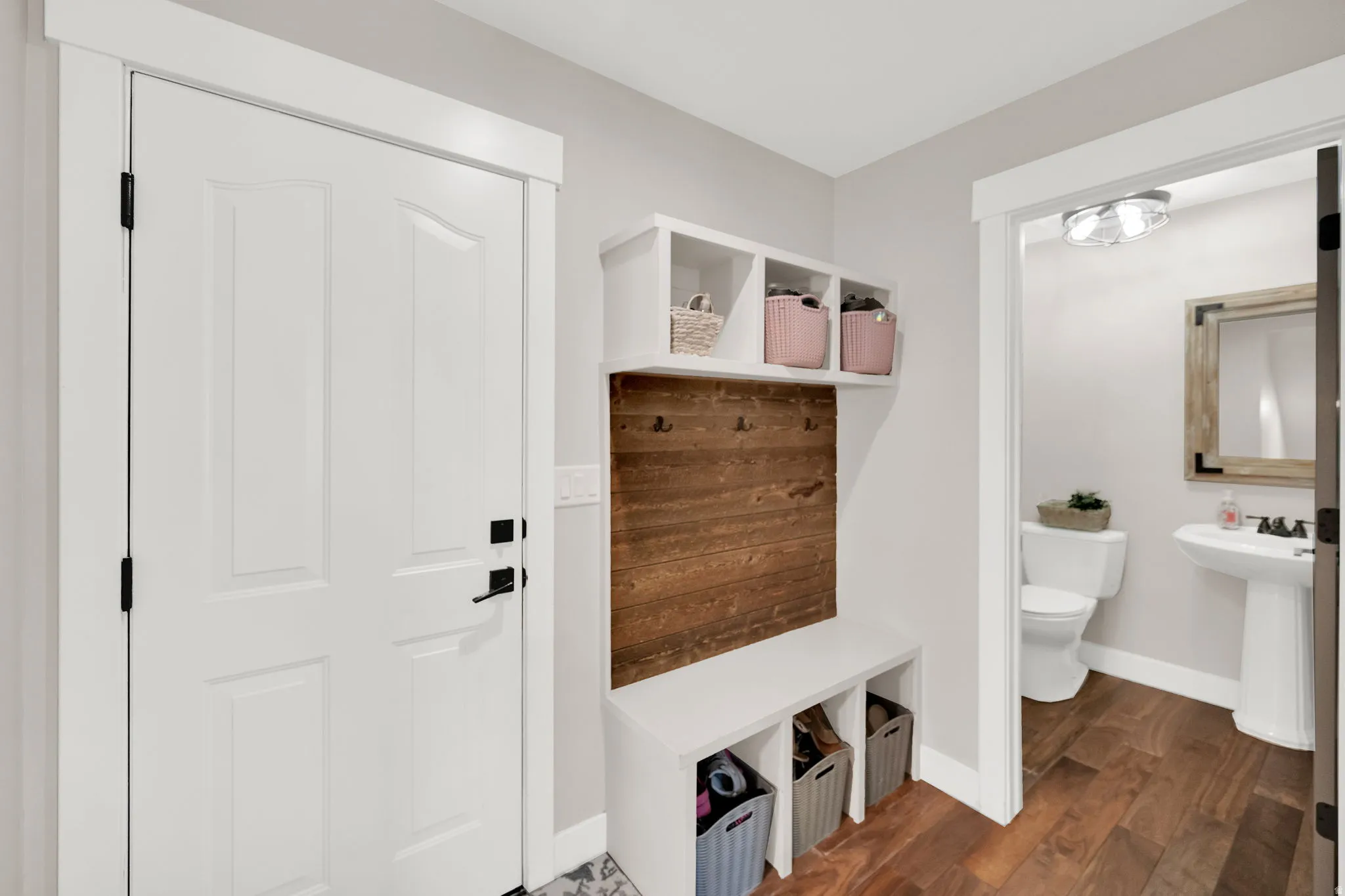 Entryway mudroom bench with cubby storage and rustic wood-paneled wall and half bath