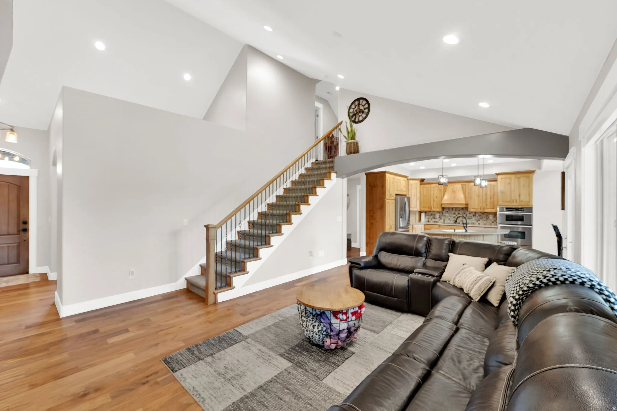Great room living area featuring hardwood flooring, a vaulted ceiling with recessed lighting.