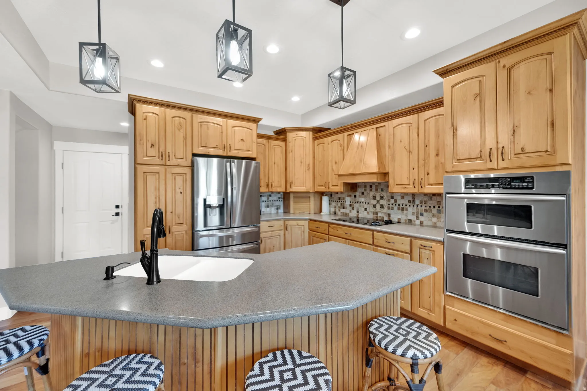Kitchen featuring light wood cabinetry, stainless steel appliances, and a gray solid surface countertop island.