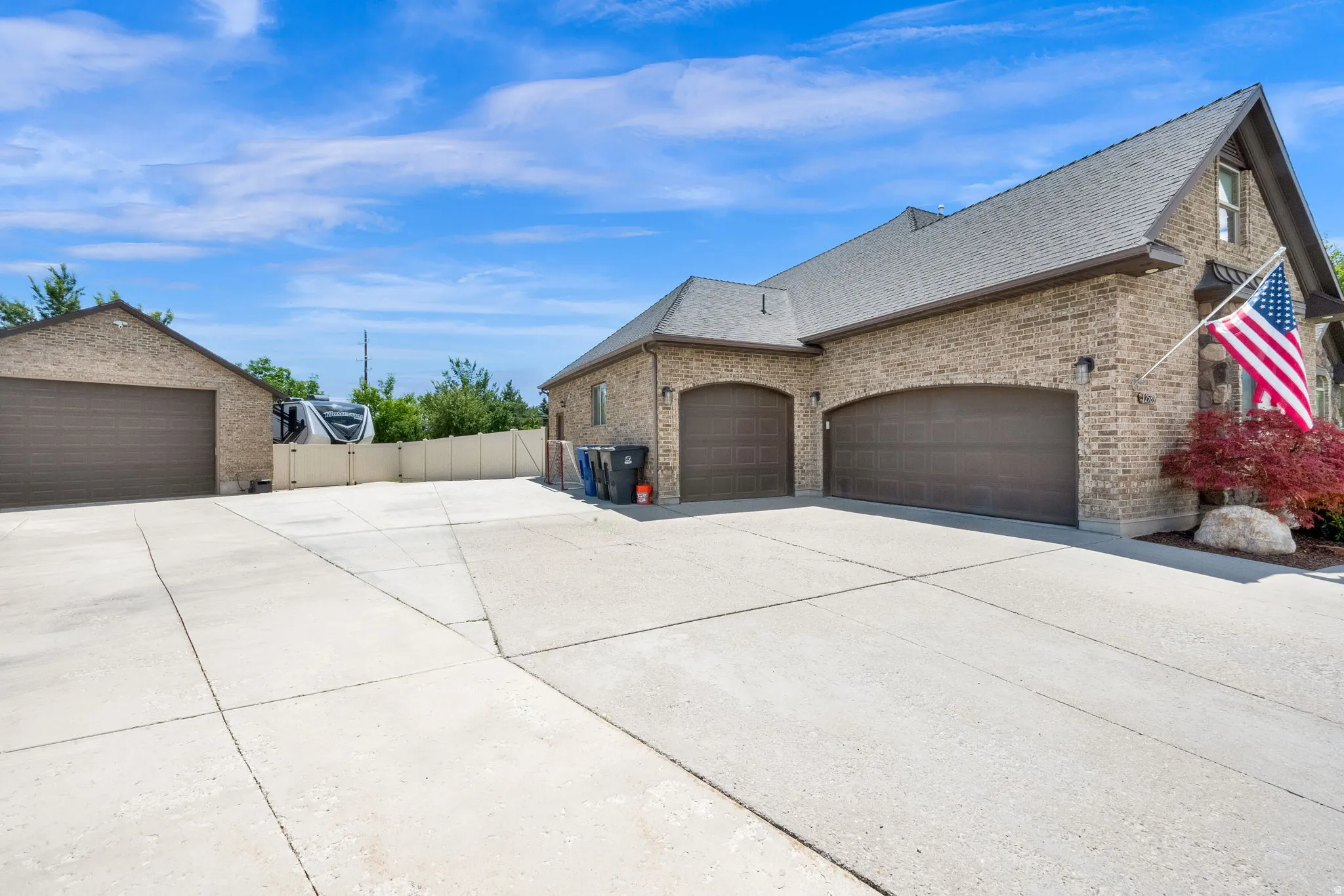 Expansive concrete driveway servicing a three-car attached garage and a detached  4-car garage