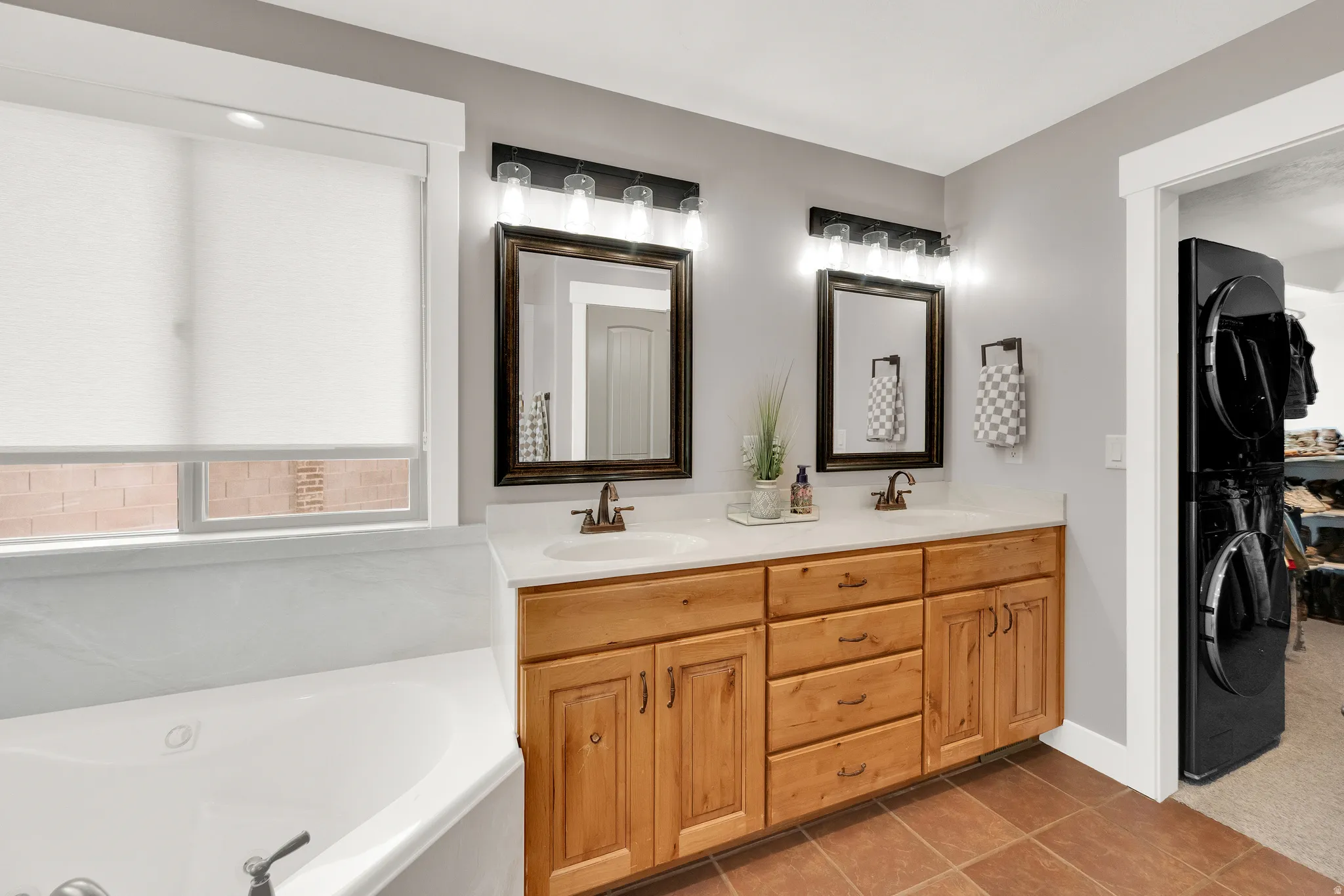 Dual vanity with light wood-finish cabinetry, white countertops, and bronze-finish fixtures