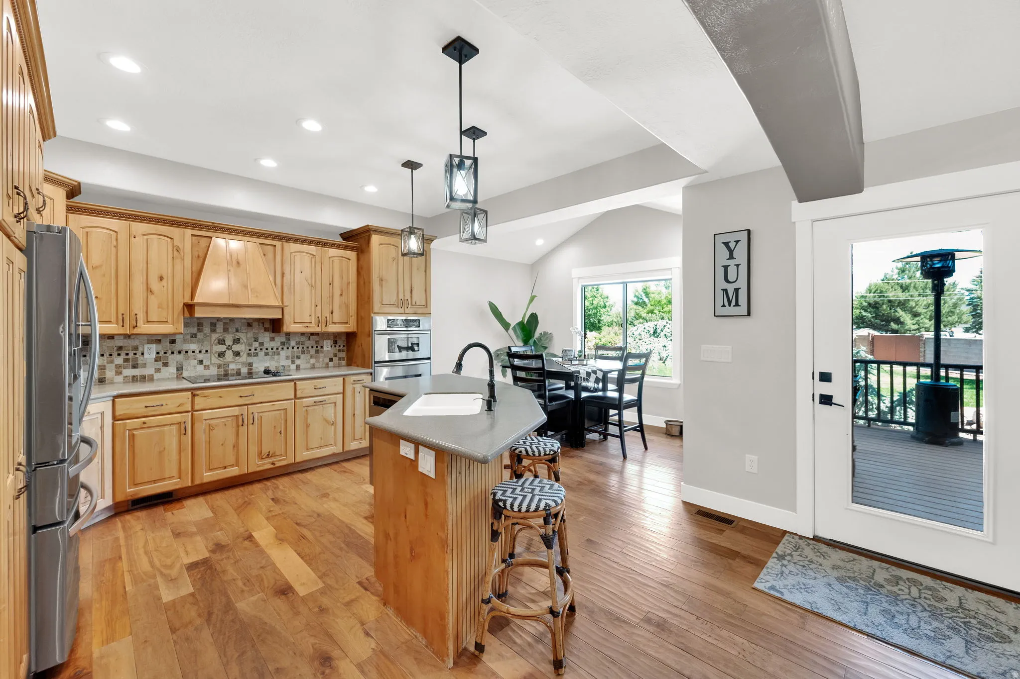 Kitchen featuring natural wood cabinetry, a mosaic tile backsplash, stainless steel built-in appliances, and wood-finish flooring