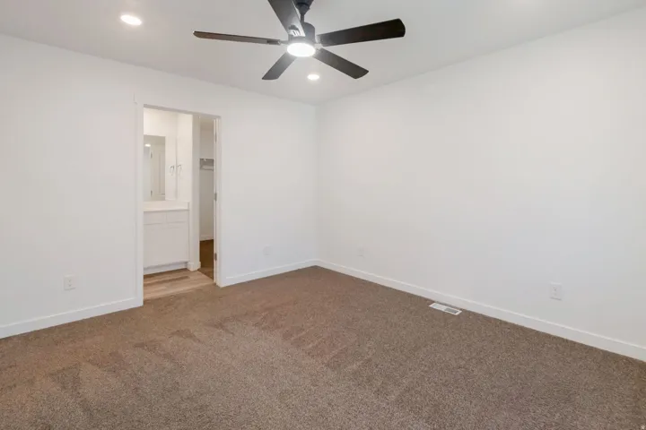 Bedroom featuring neutral-toned carpeting, white walls, and a contemporary ceiling fan with integrated lighting