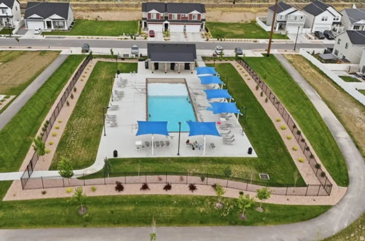 Community swimming pool featuring a two-tone water area, surrounding concrete deck, and multiple lounge chairs