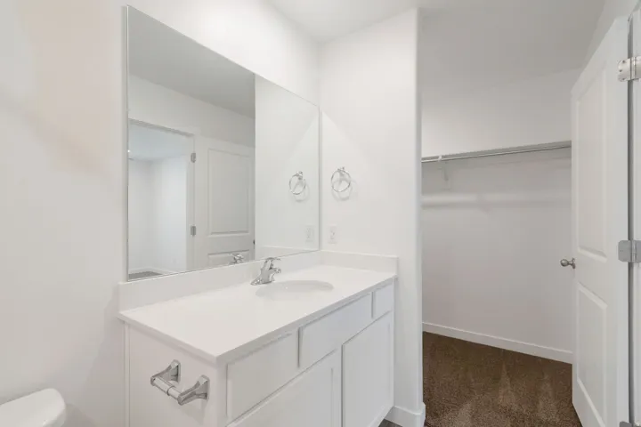 Bathroom vanity featuring a single basin sink, chrome faucet, white countertop, and white cabinetry