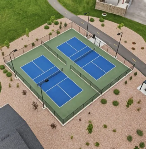 Two blue and green hard courts with black perimeter fencing
