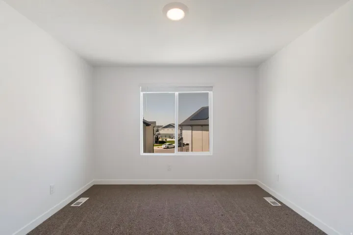 Neutral wall finishes, a single window, and plush carpet flooring