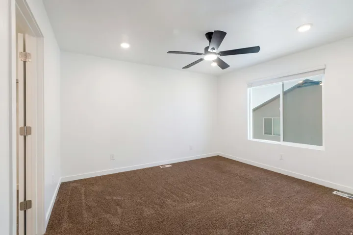 Spacious room featuring neutral carpeting, a modern ceiling fan, recessed lighting, and a large window