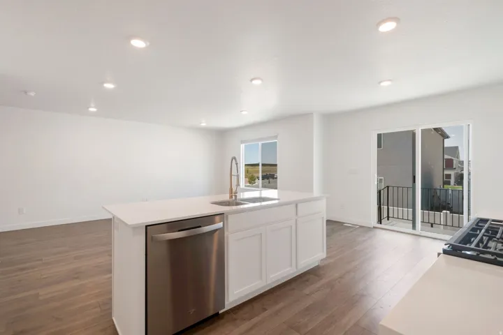Kitchen island featuring a stainless steel dishwasher, an undermount sink with a gooseneck faucet, and white cabinetry