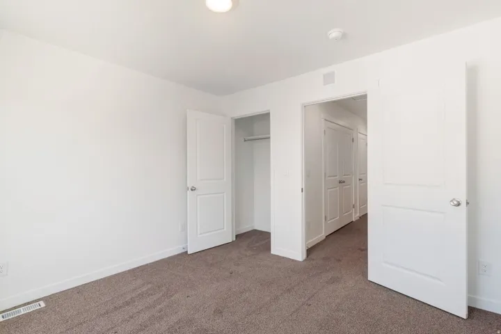 Carpeted room with white walls, recessed lighting, and a closet with bifold doors