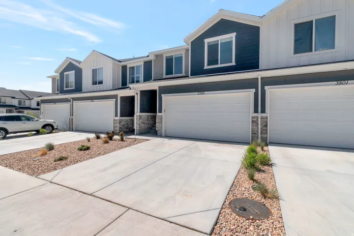 Modern townhome exterior featuring multi-toned siding, white trim accents, and a stone facade