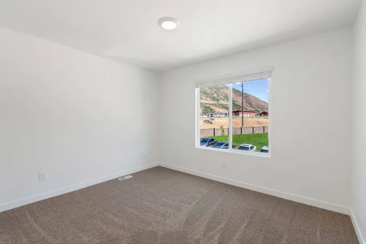 Neutral white walls with recessed lighting and a single window featuring a roller shade