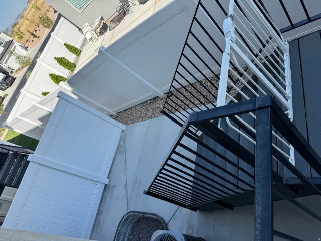 White vinyl fencing encloses a concrete patio area with decorative gravel accents