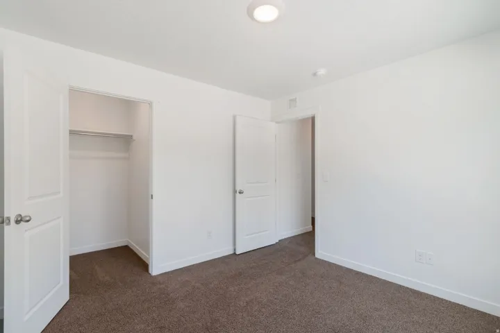 Bedroom featuring white walls, brown carpet flooring, and a built-in closet with double doors