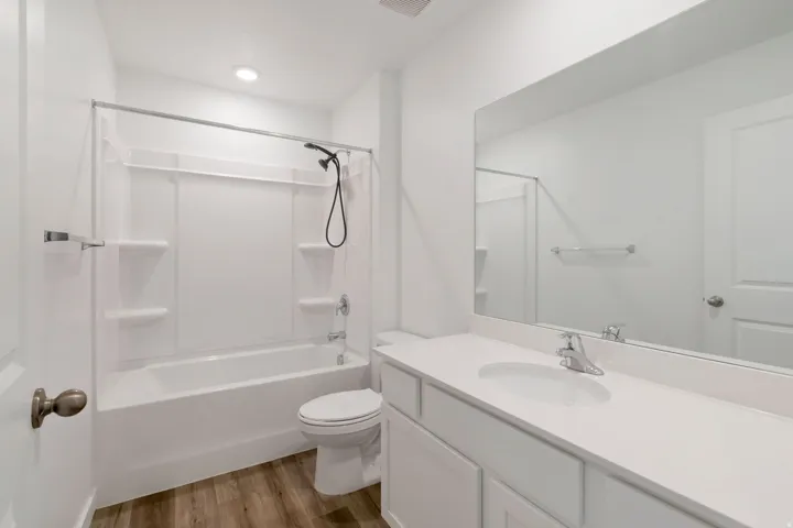 Bathroom featuring a full tub/shower combination, a large vanity with an integrated sink, a spacious wall-mounted mirror, wood-finish flooring, and recessed lighting