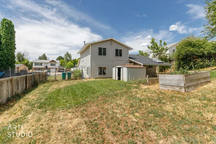 Expansive backyard featuring a wood fence, a detached shed, and a raised garden bed