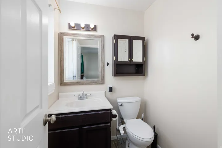 Bathroom featuring a dark wood-finish vanity with an integrated sink, framed mirror, wall-mounted light fixture, and a dark wood-finish medicine cabinet