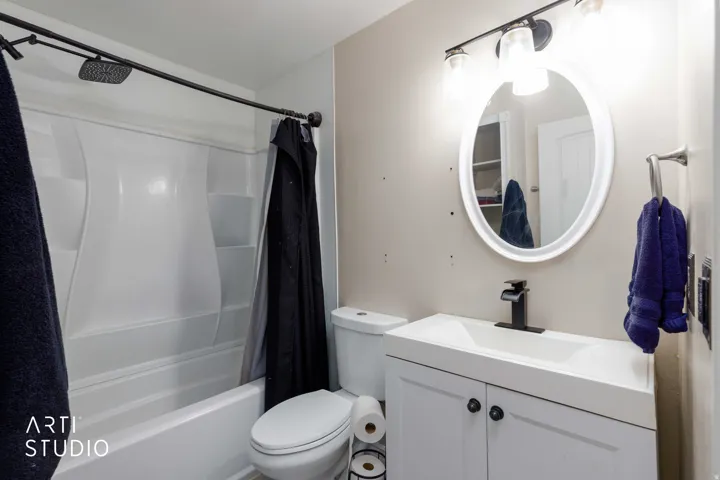 Bathroom featuring a white vanity with cabinet storage, integrated sink, and matte black faucet