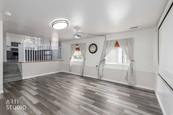 Spacious open-concept living area featuring wood-finish flooring, recessed ceiling light, and direct access to the kitchen