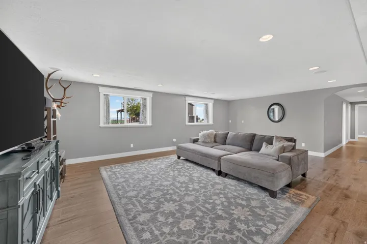 Recessed lighting, wood-finish flooring, two windows with white trim, and a curved archway