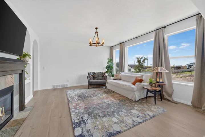 Bright living area featuring wood-finish flooring, a contemporary fireplace with a stone surround, an arched entryway, and large windows