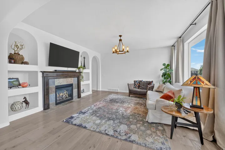 Living area with wood-finish flooring, built-in shelving, and a tiled fireplace