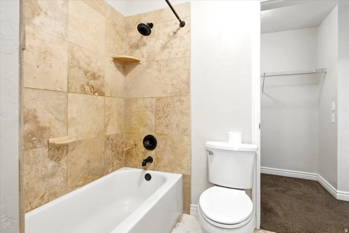 Full bathtub with stone-look tile surround and oil-rubbed bronze fixtures