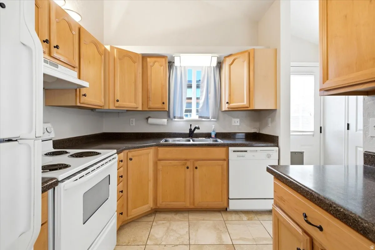Kitchen featuring light wood cabinetry, dark speckled countertops, and a tile floor