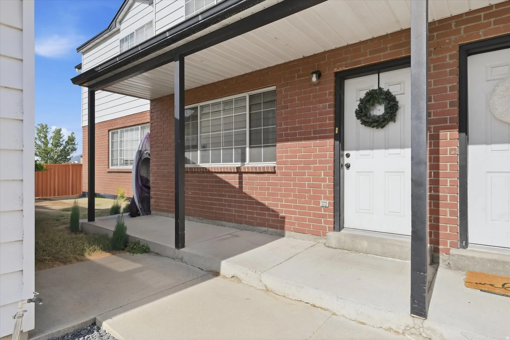 Brick facade with white siding and a covered entry
