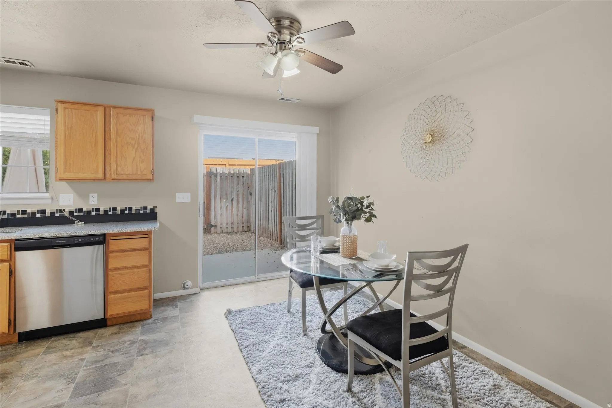 Kitchen dining area featuring wood cabinetry, stainless steel dishwasher, and a glass sliding door