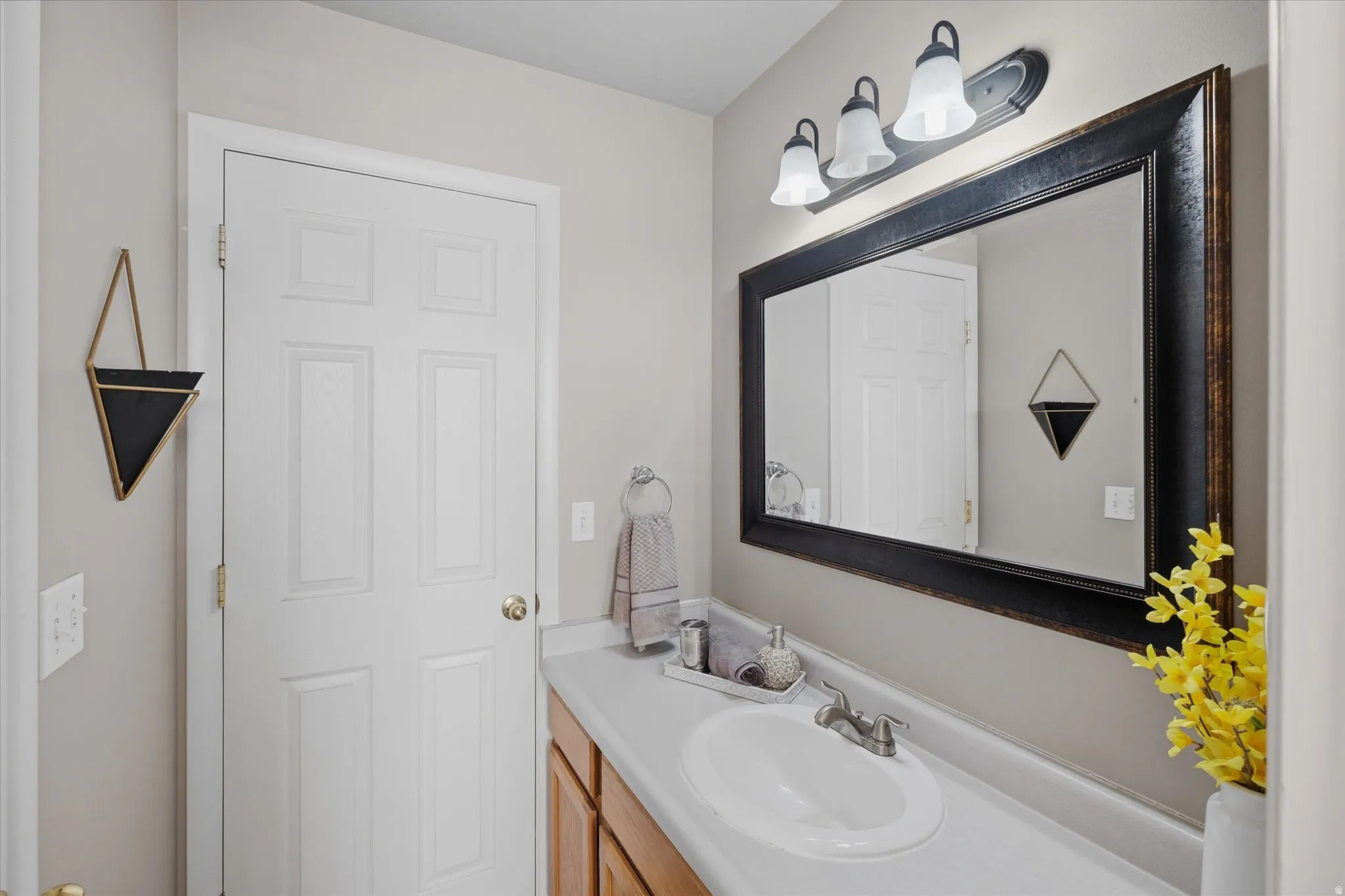 Bathroom vanity with an integrated sink, a large framed mirror, and a three-light fixture