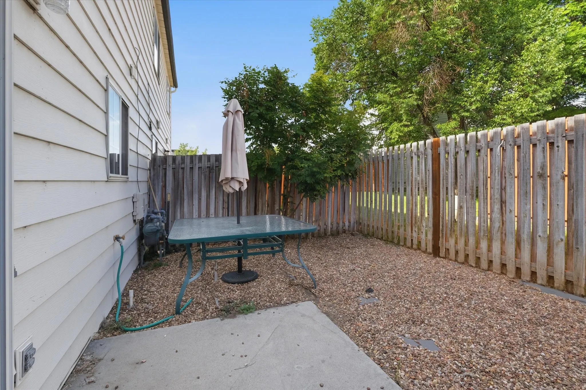 Private outdoor space featuring a concrete patio area, gravel landscaping, and wood privacy fencing