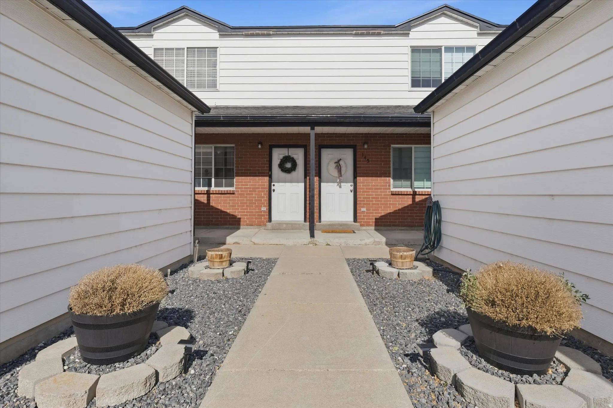 Exterior facade featuring white siding, brick accents, and a dual-entry design