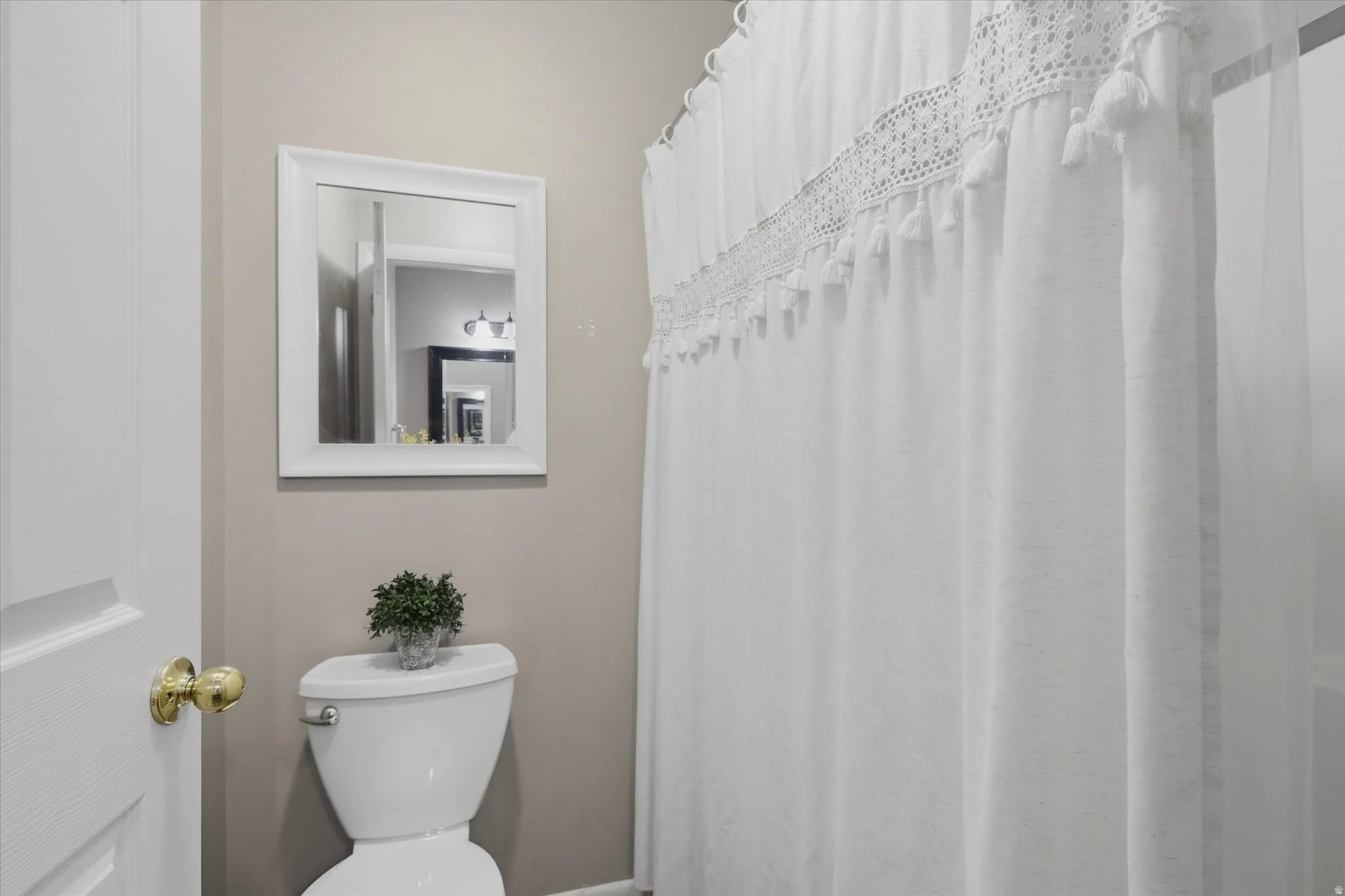 Full bathroom featuring a white toilet, framed wall mirror, and neutral wall paint